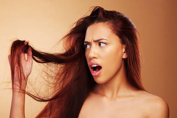 Beschädigte Haare und eine Frau ärgern sich im Studio über Salon, Split End und Friseurbehandlung. Stress, Desaster und schockierte Modelperson mit trockener Textur oder Frisurenkrise auf braunem Hintergrund. - Foto, Bild