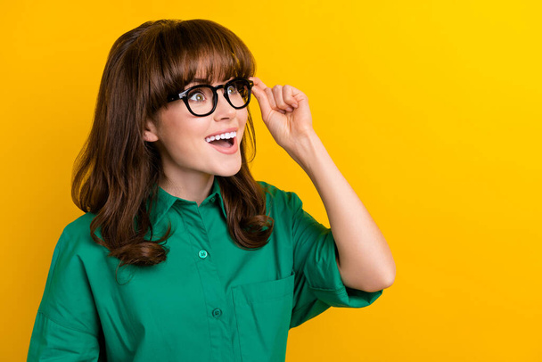 Portrait of astonished pretty lady hand touch glasses look interested empty space isolated on yellow color background. - Фото, зображення