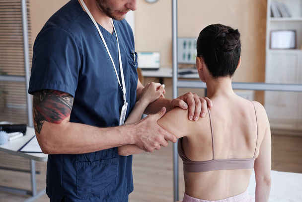 Massagetechniker in Uniform untersucht Körper des Patienten vor Massagevorgang im Krankenhaus - Foto, Bild