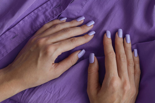 Vrouwelijke handen met gelige manicure en nagels van paarse kleur. Lavendelnagels. Permanente nagellak - Foto, afbeelding