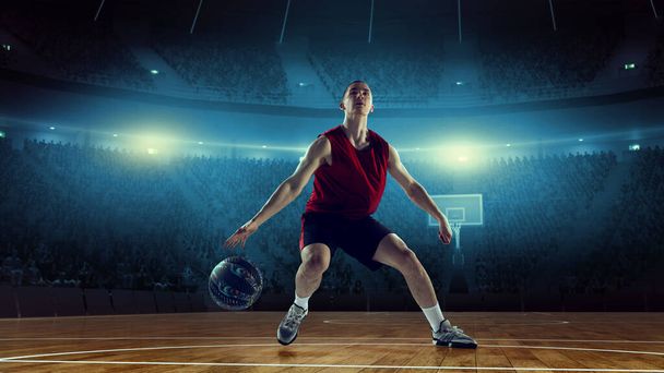 Concentrated and motivated young man, athlete, basketball player in motion during game, playing on 3D arena, stadium with flashlights. Concept of professional sport, competition, action, hobby, game. - Fotografie, Obrázek