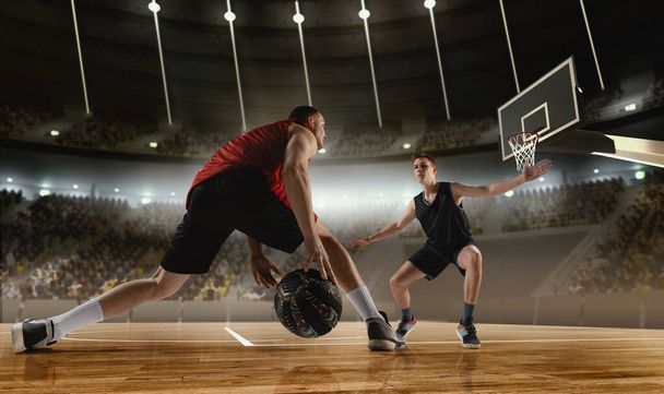 Competitive young men, basketball players in motion during match, game playing at 3D arena with flashlights. Scoring winning goal. Concept of professional sport, competition, action, hobby, game. - Photo, Image