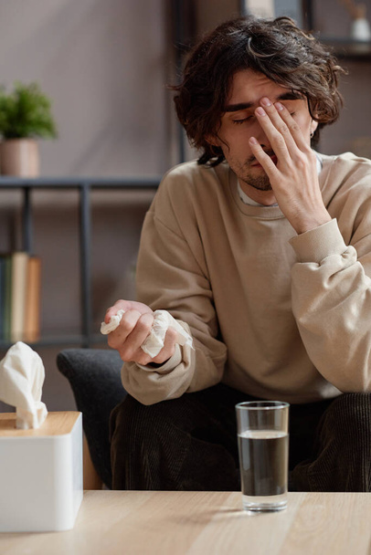 Vertical medium portrait of young Caucasian man feeling stressed out having psychologist appointment holding napkin and crying - Fotografie, Obrázek