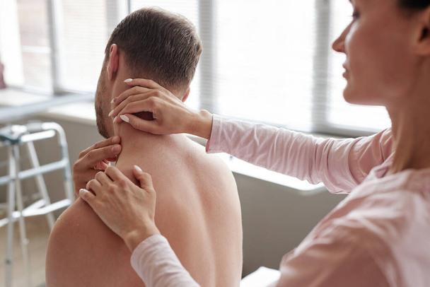 Vrouwelijke massage therapeut onderzoeken nek van de patiënt tijdens de medische procedure in het ziekenhuis - Foto, afbeelding