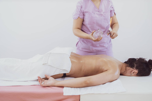 Hijama thérapie avec ventouses chauffées sur la peau du patient pour guérir les problèmes de douleur. - Photo, image