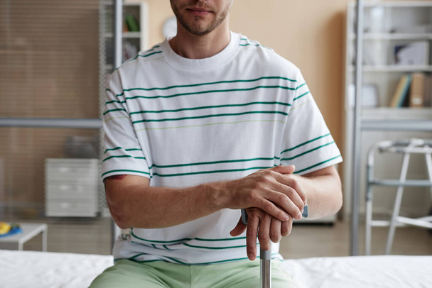 Primer plano del paciente sentado en el sofá con muleta durante su visita al hospital - Foto, Imagen