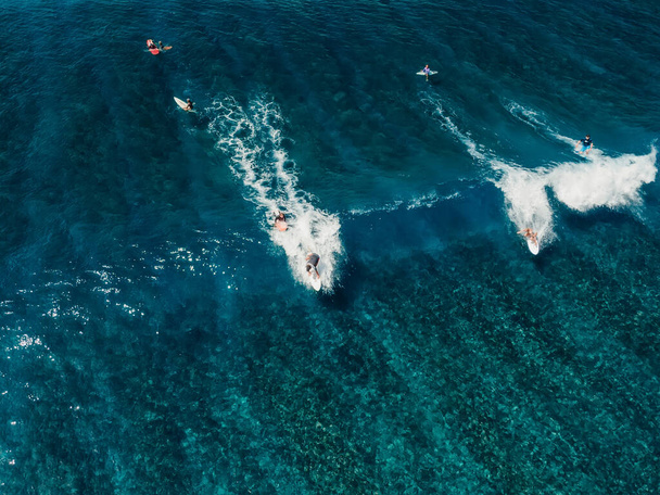 Légi felvétel, szörfözés a kék hullámon. Tökéletes hullámok szörfösökkel a trópusi óceánban - Fotó, kép