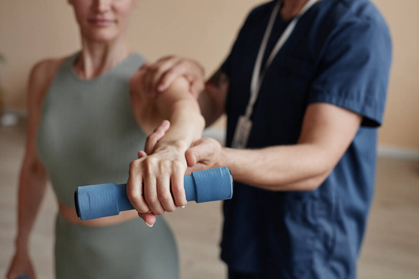 Close-up of patient training with dumbbells together with therapist in hospital - Photo, Image
