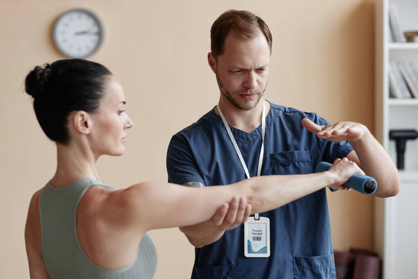 Młoda kobieta trenuje z hantlami wraz z terapeutą podczas rehabilitacji w szpitalu - Zdjęcie, obraz