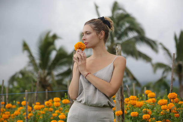 Porträt einer kaukasischen Touristin im Feld der blühenden Ringelblumen auf der Insel Bali - Foto, Bild
