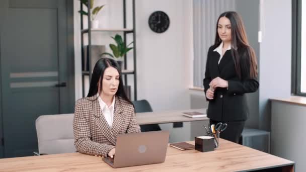 Female manager insurer consulting customer with laptop at meeting, young saleswoman showing online presentation of deal benefits talking convincing client sit at desk. The realtor hands over the keys - Footage, Video