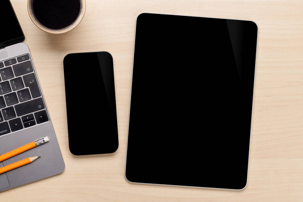 Smartphone e tablet con schermo bianco su una scrivania, perfetti per il tuo modello di design - Foto, immagini