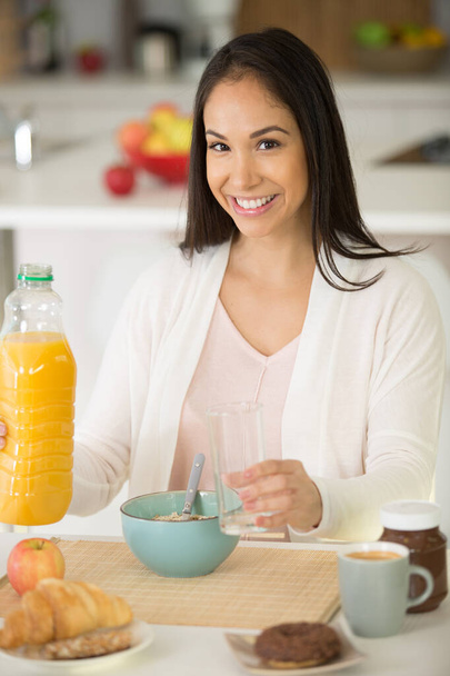 smiling pretty woman having breakfast in a kitchen - Photo, Image
