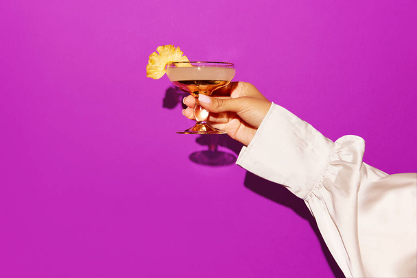Mujer mano sosteniendo cóctel margarita sobre fondo violeta brillante. Concepto de diseño, fiesta, relax, pop art. Copiar espacio para anuncio. - Foto, Imagen