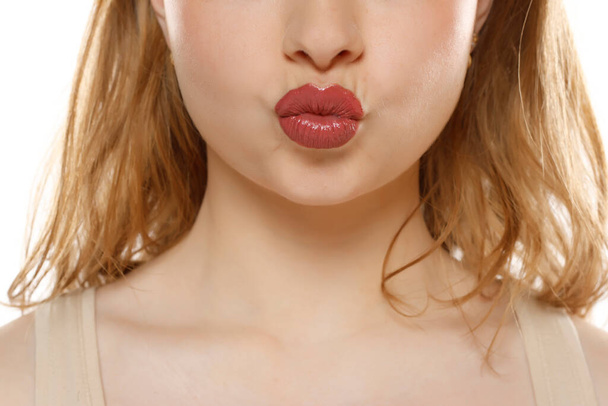 Closeup of a woman making kissing gesture on a white studio background - Photo, Image