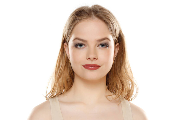 Πορτρέτο της νεαρής όμορφης ξανθιάς γυναίκας με μακιγιάζ σε λευκό φόντο στούντιο - Φωτογραφία, εικόνα