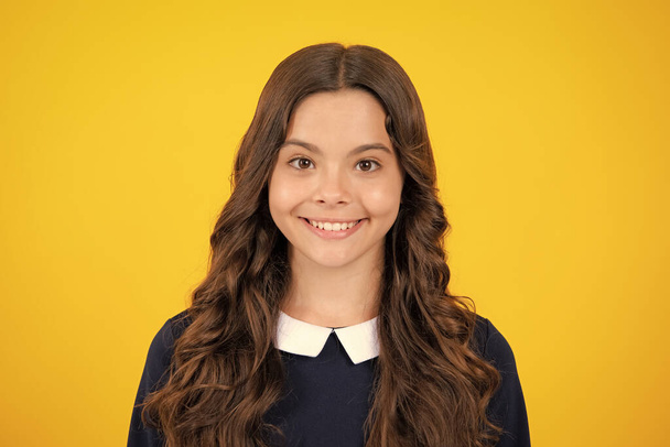 Portrait of beautiful happy smiling teenage girl on yellow studio background - Photo, Image