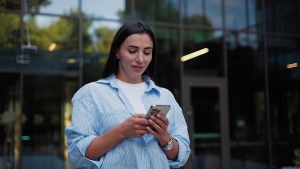 Gyönyörű fiatal üzletasszony séta sms gépelés üzenet a mobiltelefon - Felvétel, videó