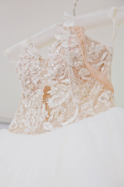 The delicate bride's dress is hanging in room. Selective focus. Close-up. - Foto, Imagem