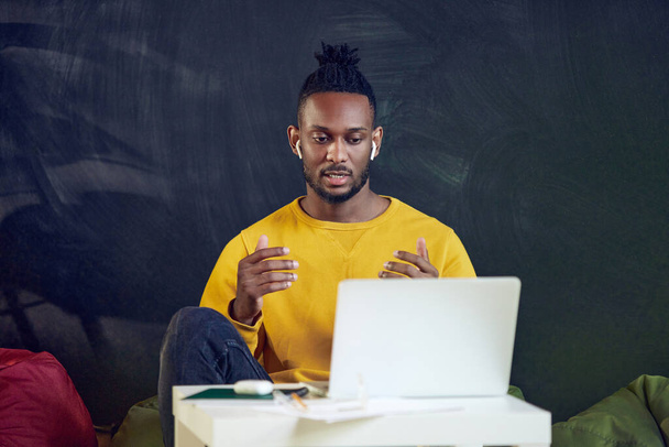 Young african man working remotely online, leading online video call with colleagues, discussing projects, gesturing. Concept of business and education, freelance job, modern lifestyle - Φωτογραφία, εικόνα