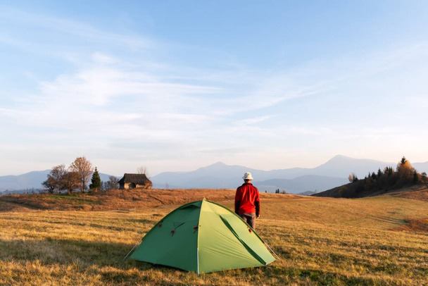 Tourist in red jacket near his tent in mountains camp. Ukrainian Carpathians, Ukraine - Фото, зображення