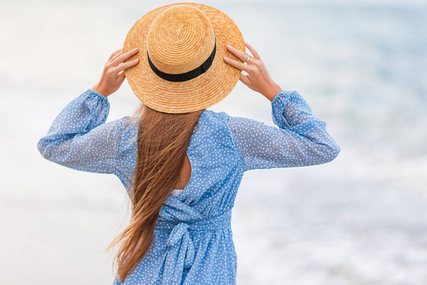Sahilde giyinmiş güzel bir kız eğleniyor. Mutlu kız yaz tatilinin tadını çıkar Mavi gökyüzü ve denizdeki turkuaz su  - Fotoğraf, Görsel