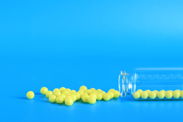 Sárga tablettákat öntenek ki egy üveg üveg kék alapon. Aszkorbinsav, oldalnézet, másolás. Egészségügyi ellátás, orvosi tabletták és étrend-kiegészítők. C-vitamin - Fotó, kép