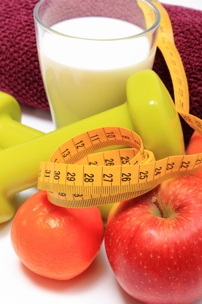 Frutas, cinta adhesiva, leche, pesas verdes y toalla púrpura sobre blanco
 - Foto, imagen
