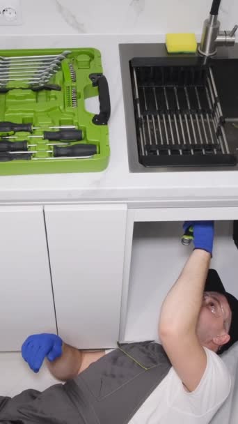Top view of a plumber repairing a sink in a kitchen room. Calling a plumber to the house. - Video