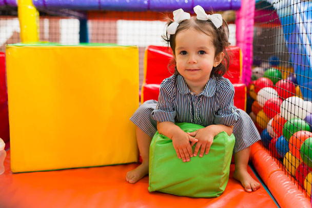 Adorable niño jugando con cubos de espuma en la sala de juegos para niños y disfrutando de un juego en la fosa de bolas del patio de recreo - Foto, imagen
