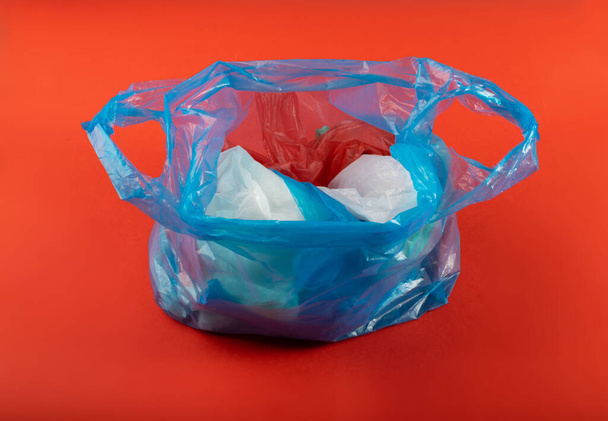 Wiele plastikowych toreb na czerwonym tle, pognieciona plastikowa torba po zakupach, odpady opakowaniowe celofanu, zużyta pognieciona jednorazowa torba - Zdjęcie, obraz
