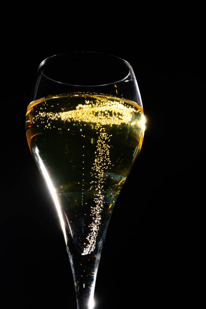 Бокал французского игристого шампанского с пузырьками на темном фоне, золотые пузырьки закрываются - Фото, изображение