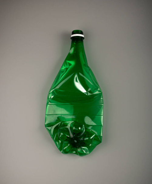 Bottiglia di plastica vuota verde, Bottiglia di plastica stropicciata, Concetto di inquinamento globale, Bottiglie di animali domestici schiacciati su sfondo grigio - Foto, immagini