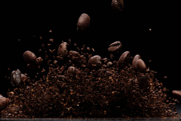 Coffee powder fly explosion, Coffee crushed ground float pouring, wave like smoke smell. Coffee ground powder splash throwing in mid Air. Black background Isolated selective focus blur - Photo, Image