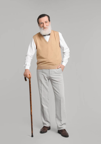 Senior man with walking cane on light gray background - 写真・画像