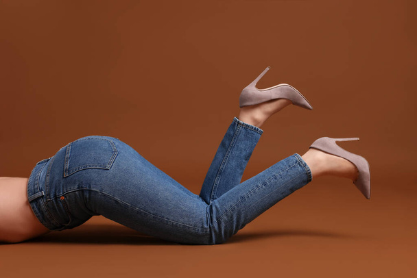 Woman in stylish jeans on brown background, closeup - Φωτογραφία, εικόνα