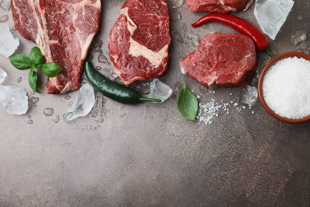 Flat lay composition with cut fresh beef meat on brown table. Space for text - 写真・画像