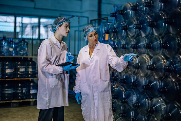 Experienced manufacturing supervisor coaches and mentors trainee in quality control. Examining sequence, inventory, physical standard for precise and effective seamless of drinking water distribution - Foto, Bild