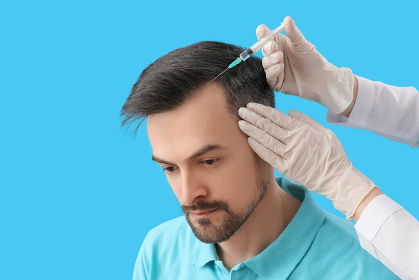 Bell'uomo che riceve l'iniezione per la crescita dei capelli su sfondo blu, primo piano - Foto, immagini