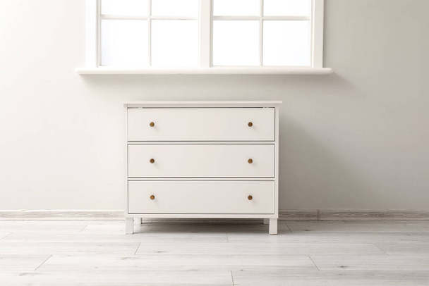 Stylish white chest of drawers near window - Foto, imagen