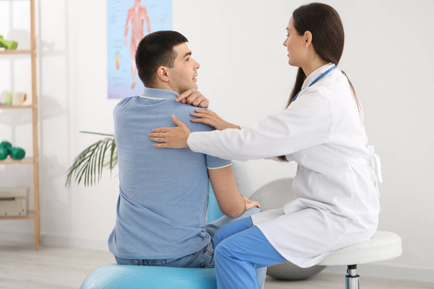 Female doctor checking posture of young man in clinic - Photo, Image