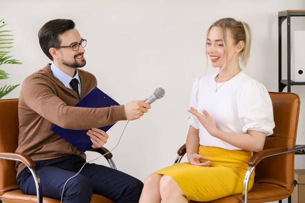 Periodista masculino con micrófono teniendo una entrevista con una mujer en el estudio - Foto, imagen