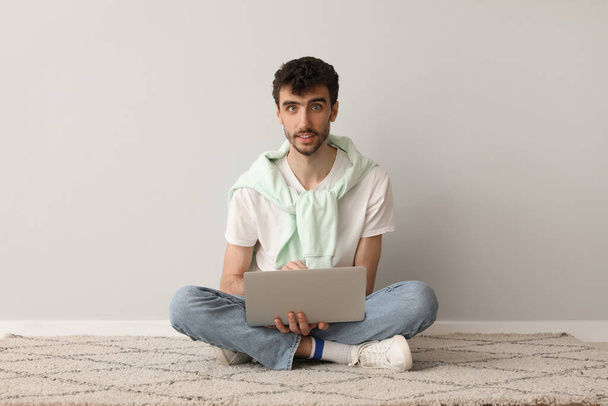 Młody człowiek pracujący z laptopem przy ścianie - Zdjęcie, obraz