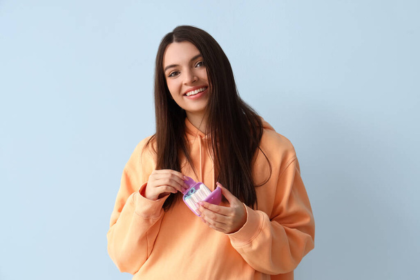 Young woman with case of tampons on blue background - Fotoğraf, Görsel