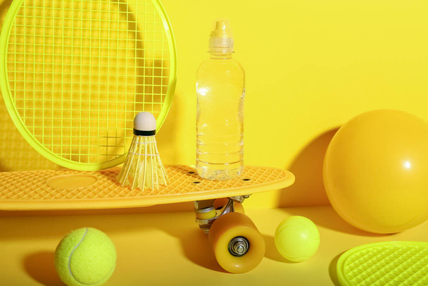 Set sportartikelen met flesje water op gele achtergrond - Foto, afbeelding