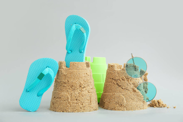 Castle made of sand with beach accessories and toy bucket on grey background - Фото, изображение