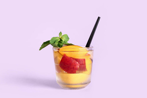 Copa de limonada fresca de melocotón con menta sobre fondo lila - Foto, Imagen