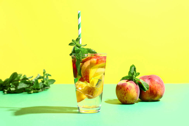 Glass of fresh peach lemonade with mint on colorful background - Photo, Image