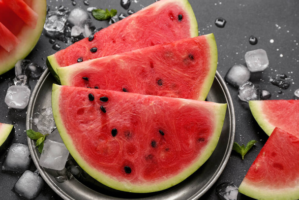 Talíř s kousky sladkého melounu a kostky ledu na černém pozadí - Fotografie, Obrázek