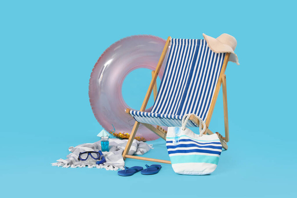 Deckchair, inflatable ring and glass of cocktail on blue background - Photo, Image